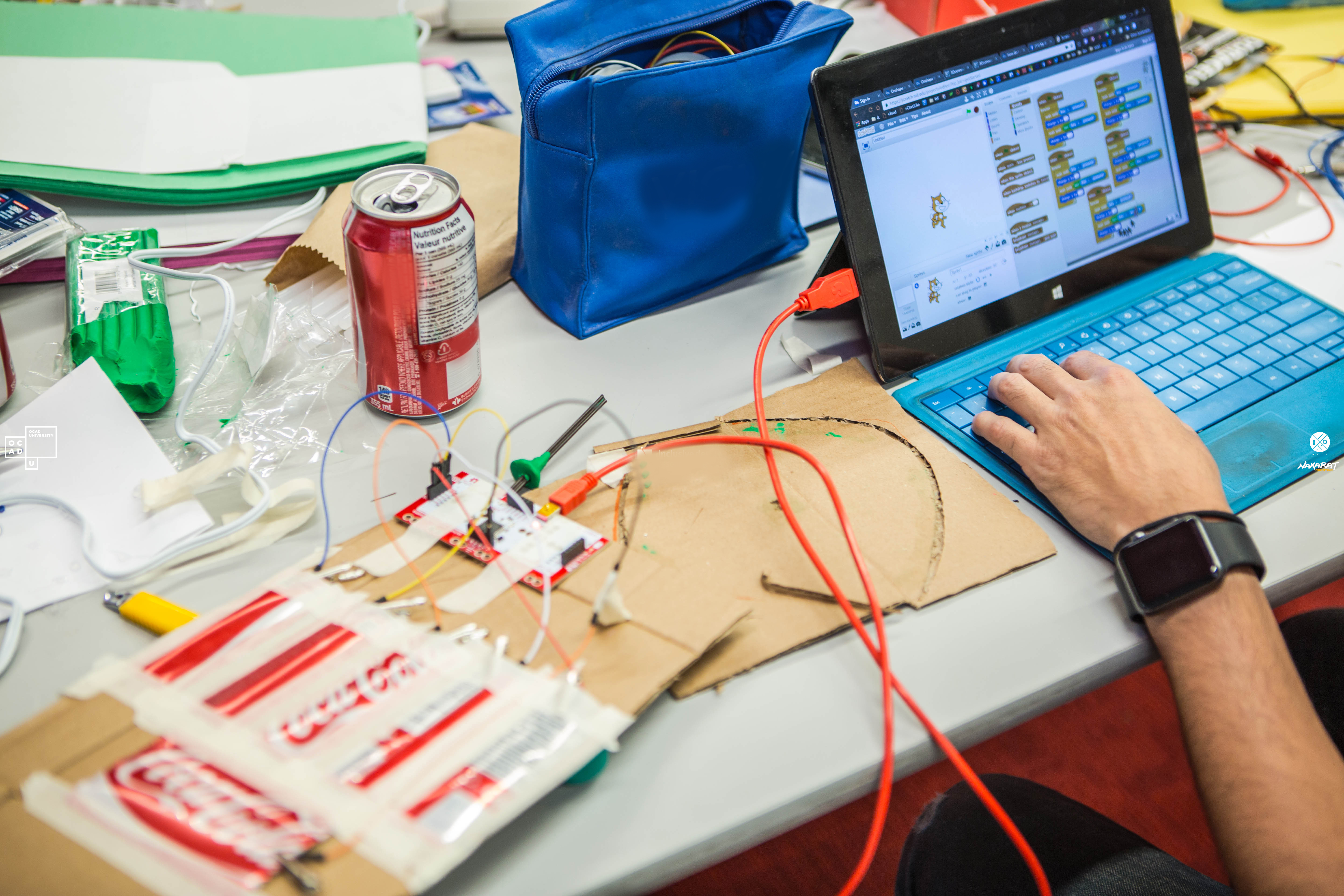 Closeup of a person working on the laptop next to Arduino which is an open-source platform, both hardware and software, used for building interactive electronic projects